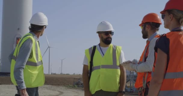 Ingenieros inspeccionan obra cerca de molino de viento — Vídeo de stock