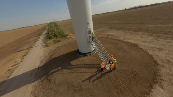 Група інженерів, які ходять і розмовляють на вітроелектростанції — стокове фото