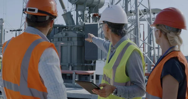 Ingeniera discutiendo datos sobre tabletas con hombres — Foto de Stock