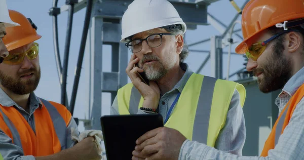 Ingeniero maduro hablando en el teléfono inteligente durante la reunión en la central eléctrica — Foto de Stock