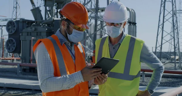 Engenheiros em máscaras usando tablet na central elétrica — Fotografia de Stock