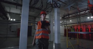 Tabletli kadın müfettiş atölyede yürüyor.