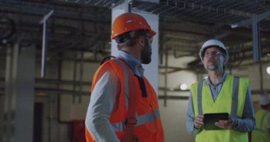 Mühendis atölyeyi müfettişe tablet kullanarak gösteriyor.