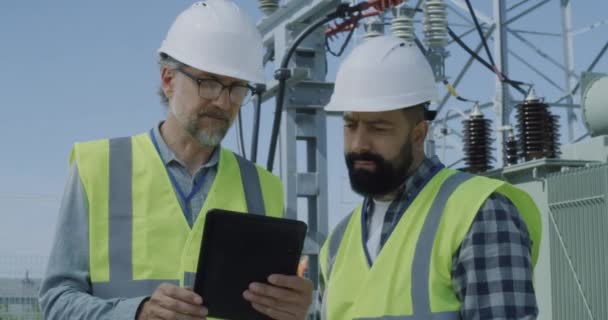 Mature engineer showing data to bearded colleague — Stock Video