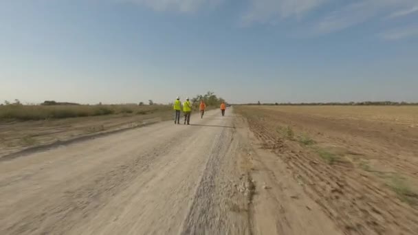 Budowniczowie spacerujący po drodze w pobliżu wiatraka na polu — Wideo stockowe