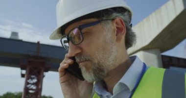 Olgun müteahhit akıllı telefondan konuşuyor.