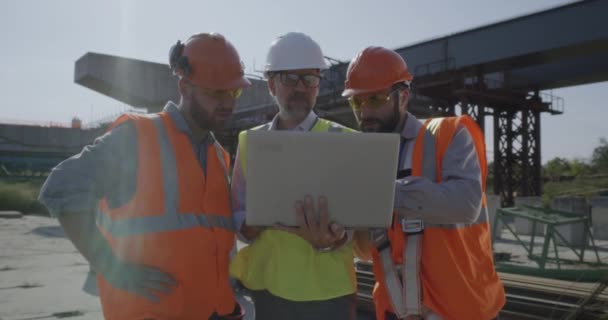 Engenheiros do sexo masculino discutindo plano no canteiro de obras — Vídeo de Stock