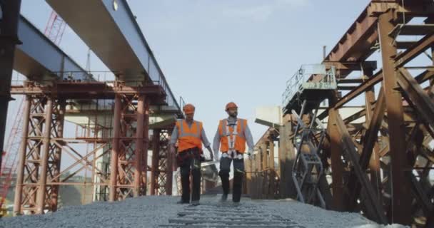 Construtores caminhando perto de ponte inacabada — Vídeo de Stock