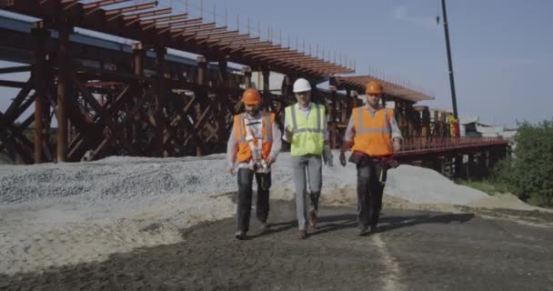 Professionella ingenjörer går mot oavslutade bron — Stockvideo