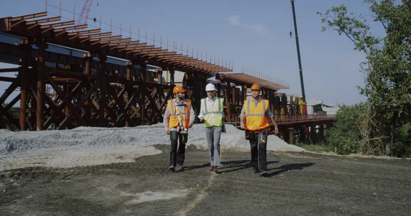 Professional engineers walking towards unfinished bridge