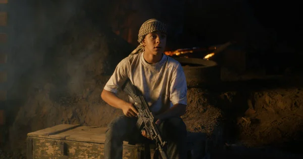 Adolescente con rifle sentado en trinchera — Foto de Stock