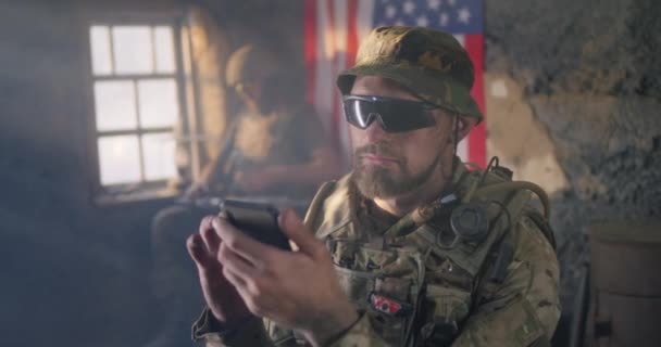 Amerikansk soldat bläddrar smartphone under krig — Stockvideo