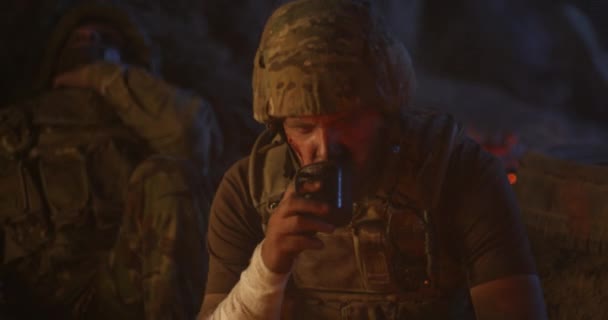 Trött soldat dricker nära lägereld — Stockvideo