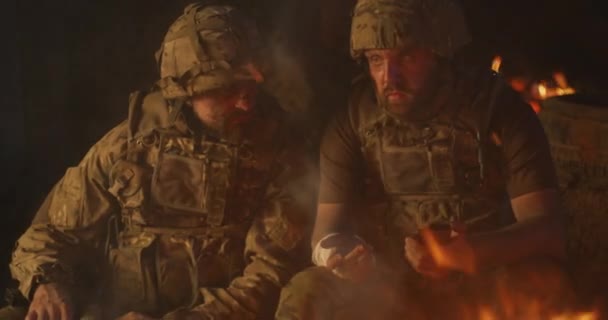 Squad mates browsing smartphone and talking near campfire — Stock Video