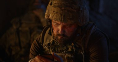 Depresyondaki asker gece ateşin yanında içiyor.