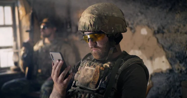 Homme militaire utilisant un smartphone à l'intérieur du bâtiment grungy — Photo