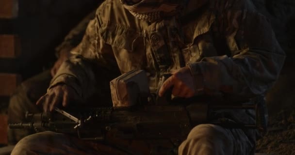 Soldier assembling gun near campfire — Stock video