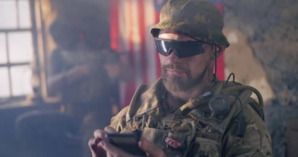 Amerikansk soldat bläddrar smartphone under krig — Stockvideo