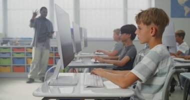 İlkokul öğrencileri bilgisayarlarda resim çiziyor, dijital sanat dersinde yaratıcı projeler üzerinde çalışıyor. Çeşitli Çocukları Eğiten Afro-Amerikan Öğretmen. İnteraktif STEM Öğrenme. Doli Vuruşu.