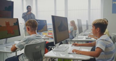 İlkokul öğrencileri bilgisayarlara resim çiziyor, dijital sanat dersinde yaratıcı projeler üzerinde çalışıyor. Dijital ekranı kullanarak çocukları eğiten Afrikalı Amerikalı öğretmen. BTMM Öğrenme. Doli Vuruşu.