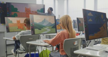 İlkokul öğrencileri bilgisayarlarda resim çiziyor, dijital sanat dersinde yaratıcı projeler üzerinde çalışıyor. Dijital ekranı kullanarak çocukları eğiten Afrikalı Amerikalı öğretmen. BTMM Öğrenme. Doli Vuruşu.