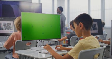 İlkokul çocuğu Chroma Key Holder ile birlikte PC Monitor 'da Yaratıcı Proje üzerinde çalışıyor. Genç Çocuklar 3D Modellik Yapıyor, Dijital Sanat Dersinde Yapay Zeka Jeneratörünü Bilgisayarlarda Kullanıyor. STEM Öğrenme.