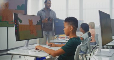 İlköğretim Okulu Çocukları Bilgisayar Kullanıyor, Dijital Resimler Oluşturuyor. Afro-Amerikan Öğretmen Dijital Sanat Dersinde Genç kızlara ve oğlanlara ders veriyor. Etkileşimli BTMM Eğitimi. Doli Vuruşu.