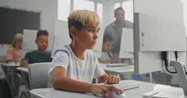 Bilgisayarda Yaratıcı Proje üzerinde çalışan genç çocuk. İlkokul öğrencileri Bilgisayar Bilimi Sınıfı 'nda Dijital Yetenekler ve Eğitim Programı uyguluyor. İnteraktif STEM Öğrenme. Görüntüyü Kapat.