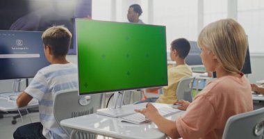 İlkokul kızı Chroma Key Holder ile PC Monitor 'da Yaratıcı Proje üzerinde çalışıyor. Bilgisayarlarda yapay zeka üreticisi kullanan, Dijital Sanatlar Dersinde İllüstrasyon Yaratan Genç Çocuklar. STEM Öğrenme.