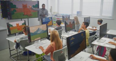 İlköğretim Okulu Çocukları Bilgisayar Kullanıyor, Dijital Resimler Oluşturuyor. Dijital ekranı kullanarak genç kızlara ve oğlanlara resim dersi veren Afrikalı Amerikalı öğretmen. BTMM Eğitim. Sabit Çekim.