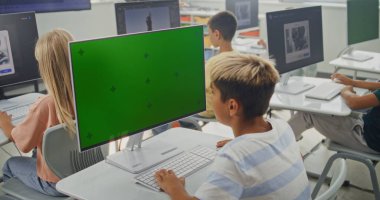 İlkokul çocuğu Chroma Key Holder ile birlikte PC Monitor 'da Yaratıcı Proje üzerinde çalışıyor. Küçük Çocuklar Yapay Zeka Jeneratörünü Bilgisayarlarda Kullanıyor, Dijital Sanat Dersinde 3D Modelleme Yapıyor. STEM Öğrenme.