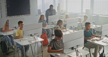 İlkokul öğrencileri bilgisayarlar üzerinde yaratıcı projeler üzerinde çalışıyorlar. Bilgisayar Bilimi dersi sırasında çeşitli çocuklara eğitim konusunda rehberlik eden Afro-Amerikan Öğretmen. Modern BTMM Öğrenme. Yüksek Açı