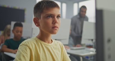 Bilgisayarda Yaratıcı Proje üzerinde çalışan genç çocuk. İlkokul öğrencileri Bilgisayar Bilimi Sınıfı 'nda Dijital Yetenekler ve Eğitim Programı uyguluyor. İnteraktif STEM Öğrenme. Görüntüyü Kapat.