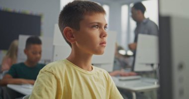 Bilgisayarda Yaratıcı Proje üzerinde çalışan genç çocuk. İlkokul öğrencileri Bilgisayar Bilimi Sınıfı 'nda Dijital Yetenekler ve Eğitim Programı uyguluyor. İnteraktif STEM Öğrenme. Görüntüyü Kapat.