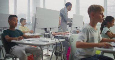 İlkokul öğrencileri bilgisayarlar üzerinde çalışıyor. Bilgisayar Bilimi Sınıfında Çeşitli Çocuklara Dijital Yetenek Uygulama ve Eğitim Programında Rehber Öğretmenlik. İnteraktif STEM Öğrenme. Doli Vuruşu.