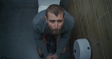 İshal ve hazımsızlık çeken ve tuvalette oturan gergin yüz ifadesi olan bir iş adamı. Adamın Karnı Karışık, Ofis Tuvaletinde Sindirim Rahatsızlığı. Üst Görünüm.