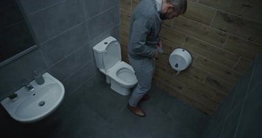 İş adamı pantolonunu çıkarıyor, tuvalette oturuyor, ishal ve hazımsızlık çekiyor. Ofis Tuvaletinde Sindirim Bozukluğu ve Sindirim Bozukluğu Yaşayan Adam. Yüksek Açı.