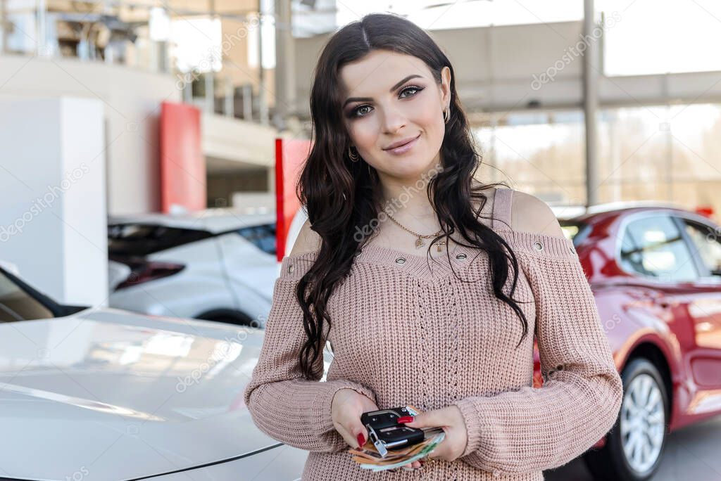 Woman with keys and euro banknotes standing near new car