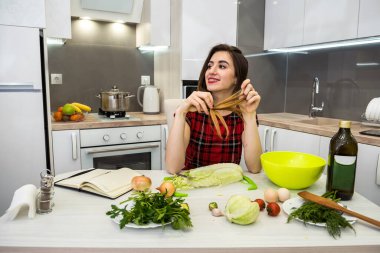 Çekici kız farklı sebzelerden ve zeytinyağlı sebzelerden oluşan bir salata hazırlıyor sağlıklı bir yaşam tarzı için.