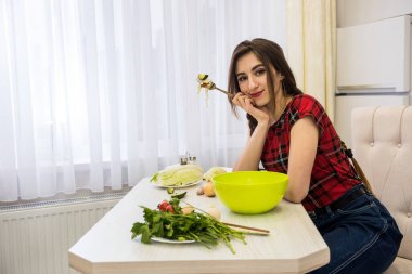 Sağlıklı bir yaşam için mutfakta sebze salatası yiyen bir kız.