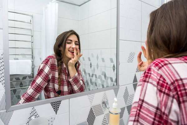 Beautiful woman applying cleansing moisturizing skin cream on face after bath. Skincare