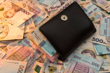 Kalın para dolu siyah adamın cüzdanı Ukrayna Hryvnia parasının zemininde yatıyor. Tasarruf kavramı