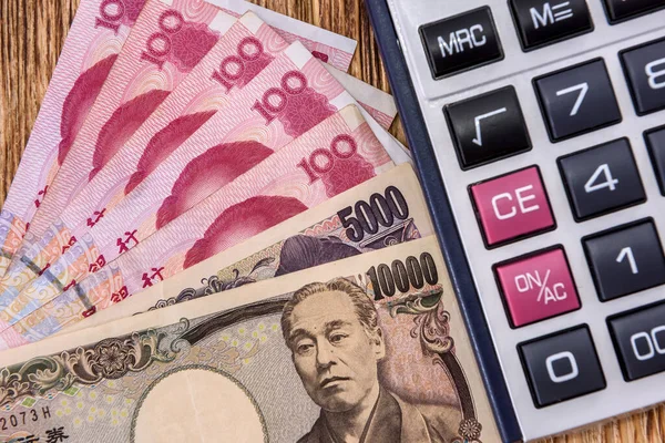 Kalkulator Chińskimi Japońskimi Banknotami Drewnianym Tle Zbliżenie — Zdjęcie stockowe