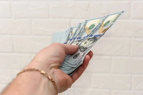 Hand with dollars pile close up on wall brick background