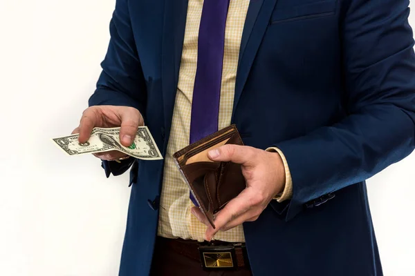 a man in a suit looks in his wallet and pulls out only $ 1. a ruined businessman. the concept of failure or bankruptcy