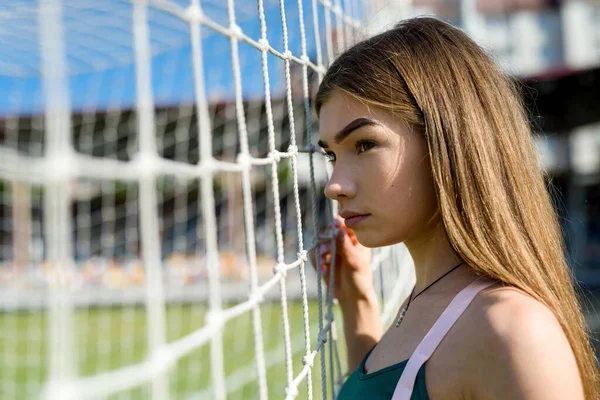 完璧な姿の美しい女の子がスタジアムのサッカーのゴールの近くに立っています フィットネスと健康的なライフスタイルのコンセプト — ストック写真