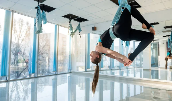 Woman practices aerial yoga in hammock . Anti-gravity relaxing kind of sport. Health, fly yoga concept.