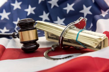 Amerika bayrağının üzerinde kelepçe ve dolar banknotları olan yargıç tokmağı. Hukuk ya da suç kavramı. Adalet