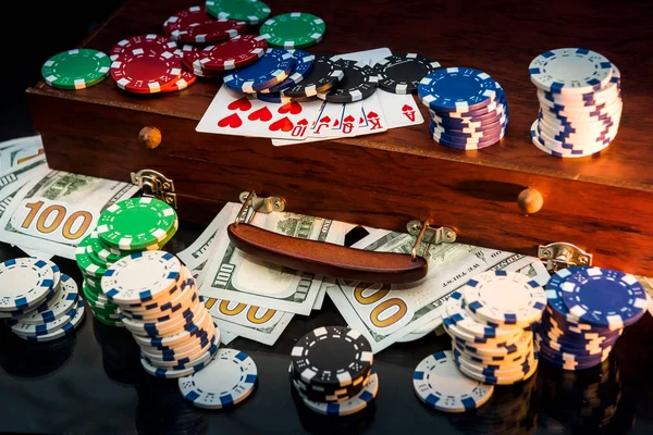 Gambling Concepts. Betting is a gamble for investors. Case full of chips, dollars and playing cards on a black background