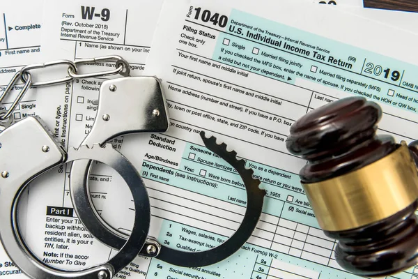 Law concept, 1040 finance tax form with gavel and handcuff. Crime and illegal system